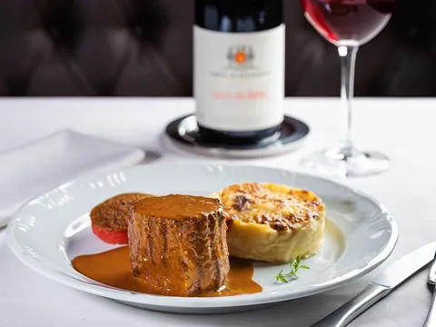 Tournedos de filé mignon ao molho Dijon com batata gratinada e vinho tinto ao fundo